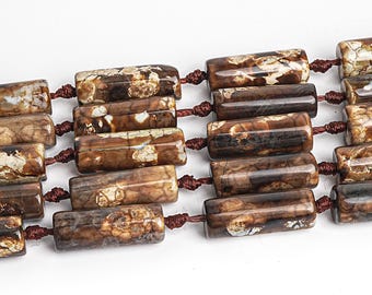 May include: A strand of brown and white agate gemstone beads. The beads are cylindrical and have a natural, organic look. They are strung on a brown cord.