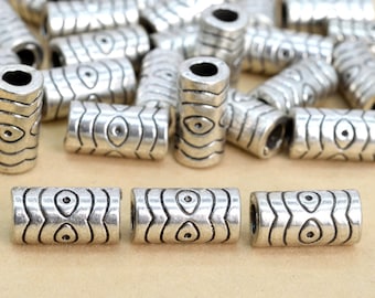 Peut inclure: Un groupe de perles en métal argenté avec un motif ondulé et un petit motif d'œil. Les perles mesurent environ 2,5 cm de long et sont parfaites pour la fabrication de bijoux ou d'autres objets artisanaux.