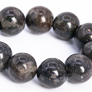 May include: A black gemstone bracelet with round beads. The beads have a speckled, iridescent finish.