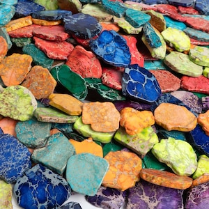 May include: A close-up of a collection of colourful, irregularly shaped, polished stones. The stones are a variety of colours, including blue, green, red, orange, yellow, and purple. The stones are arranged in a random pattern, creating a visually appealing and vibrant display.