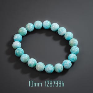 May include: A circular bracelet composed of smooth, round, light blue and white marbled beads. Each bead measures 10mm in diameter. The bracelet is arranged in a ring shape, showcasing the natural color variations and patterns of the stone material.