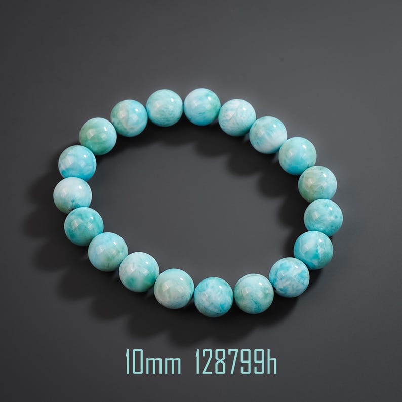 May include: A circular bracelet composed of smooth, round, light blue and white marbled beads. Each bead measures 10mm in diameter. The bracelet is arranged in a ring shape, showcasing the natural color variations and patterns of the stone material.