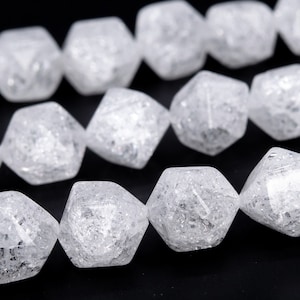 May include: A strand of white faceted glass beads with a frosted finish. The beads are shaped like a multifaceted diamond.