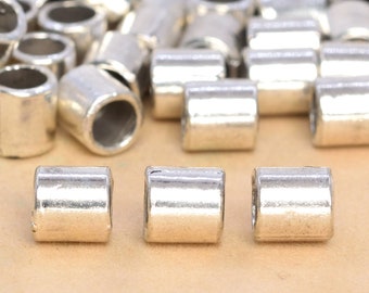 Puede incluir: Cuentas espaciadoras de metal plateado para la elaboración de joyas. Las cuentas son cilíndricas y tienen un acabado liso y brillante.