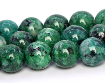 May include: A strand of green and black speckled round beads. The beads are smooth and polished.