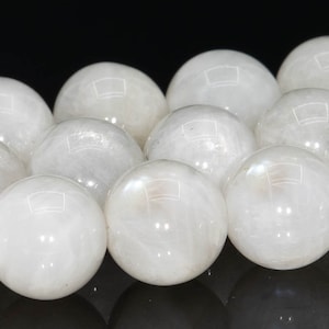 May include: A strand of white gemstone beads. The beads are round and smooth, with a slight iridescent sheen.
