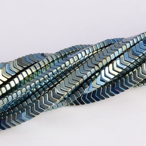 May include: A strand of blue and silver chevron-shaped beads. The beads are made of hematite and have a metallic finish.