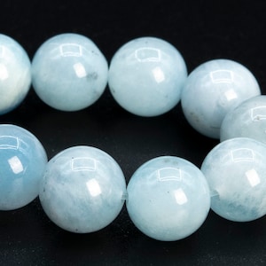 May include: A strand of light blue aquamarine beads. The beads are round and smooth, and they have a slight shimmer to them.