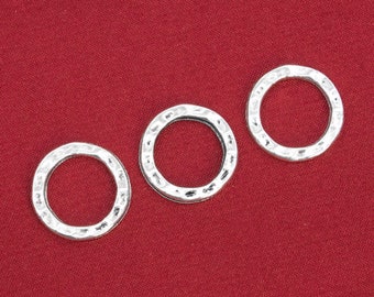 May include: Three silver-toned metal rings with a hammered texture. The rings are on a red fabric background.