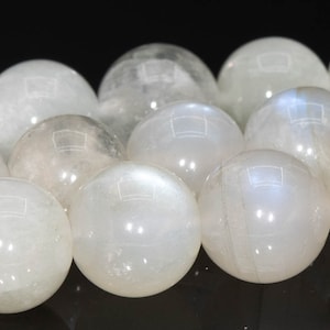 May include: A strand of white moonstone beads. The beads are round and smooth, with a slight iridescent sheen.