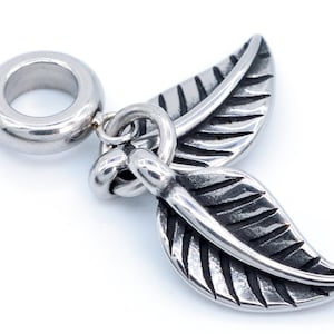 May include: Silver charm with two detailed leaf designs, attached to a round bead.