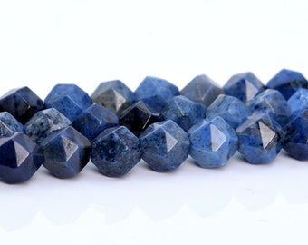 May include: A strand of blue gemstone beads with a faceted, star-shaped design. The beads are a deep blue color with a slightly mottled appearance.