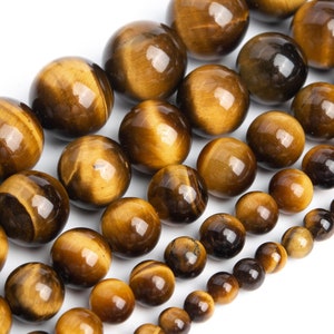 Puede incluir: Una hebra de cuentas redondas de ojo de tigre pulidas de varios tamaños. Las cuentas son una mezcla de colores marrón dorado y marrón oscuro con un efecto brillante.