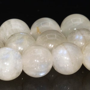 May include: A strand of white moonstone beads. The beads are round and smooth, with a slight iridescent sheen.