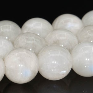 May include: A strand of white moonstone beads. The beads are round and smooth, with a subtle iridescent sheen.