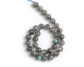 May include: A strand of round, gray labradorite beads with iridescent blue and green flashes. The beads are strung on a blue cord.