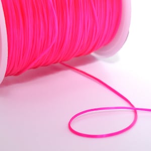 May include: A spool of bright pink elastic cord, with a small amount of cord unwound and forming a loop.