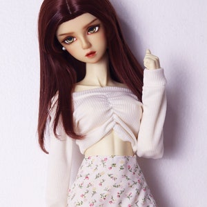 May include: A doll with long, dark brown hair wearing a white off-the-shoulder top and a floral print skirt with a lace trim.