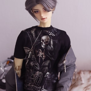 May include: A doll with grey hair wearing a black t-shirt with a skull graphic and a grey jacket.