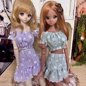 May include: A white ceramic mug with a black handle and the text "But First, Coffee" in a bold, black font. The mug is set against a blurred background, suggesting a cozy setting.