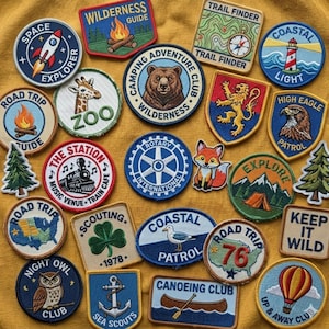 May include: A collection of embroidered patches featuring various designs including a rocket, a bear, a lighthouse, a train, a fox, a clover, a seagull, an owl, and a hot air balloon, with text such as Wilderness Guide, Trail Finder, and Keep It Wild.