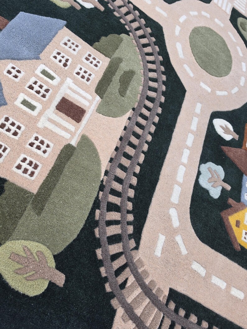 Children's railway and road map rug featuring a beautifully illustrated town with detailed train tracks, curved streets, school building, residential neighborhood, central roundabout, landscaped trees, and a blue lake with sailboat. Displayed in a bright contemporary dining room, this soft educational rug blends luxury home décor with child-friendly functionality.