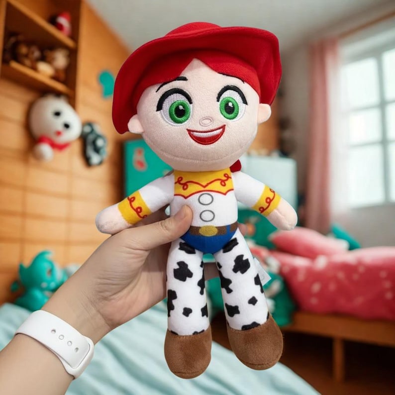 Puede incluir: Mu&ntilde;eca de peluche de un personaje con sombrero rojo, camisa blanca y pantalones con estampado de vaca. La mu&ntilde;eca tiene una cara sonriente con ojos verdes y boca roja. El atuendo incluye un peto amarillo y un cintur&oacute;n azul.