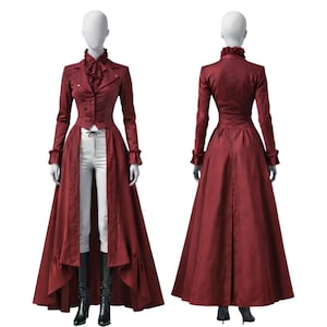 Peut inclure: Un long manteau bordeaux avec un col montant, des volants et une fermeture boutonnée. Le manteau est associé à un pantalon blanc et des bottes noires. Le manteau a une longue jupe fluide et est présenté sur un mannequin.