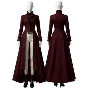 Puede incluir: Un abrigo largo burdeos con dobladillo alto-bajo, exhibido en un maniquí. El abrigo presenta un diseño a medida con una parte delantera abotonada, puños con volantes y una camisa a juego de cuello alto. Pantalones blancos y botas negras completan el conjunto.