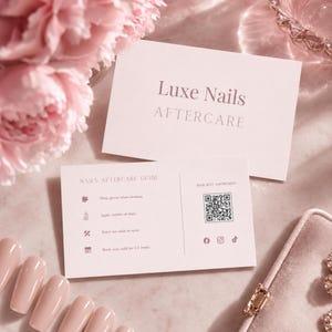 Könnte beinhalten: Zwei Luxe Nails Aftercare Karten auf rosa Hintergrund. Eine Karte trägt den Text "Luxe Nails AFTERCARE". Die andere Karte hat "NAILS AFTERCARE GUIDE" und einen QR-Code. Künstliche Nägel in Rosa sind im Vordergrund, mit rosa Blumen im Hintergrund.