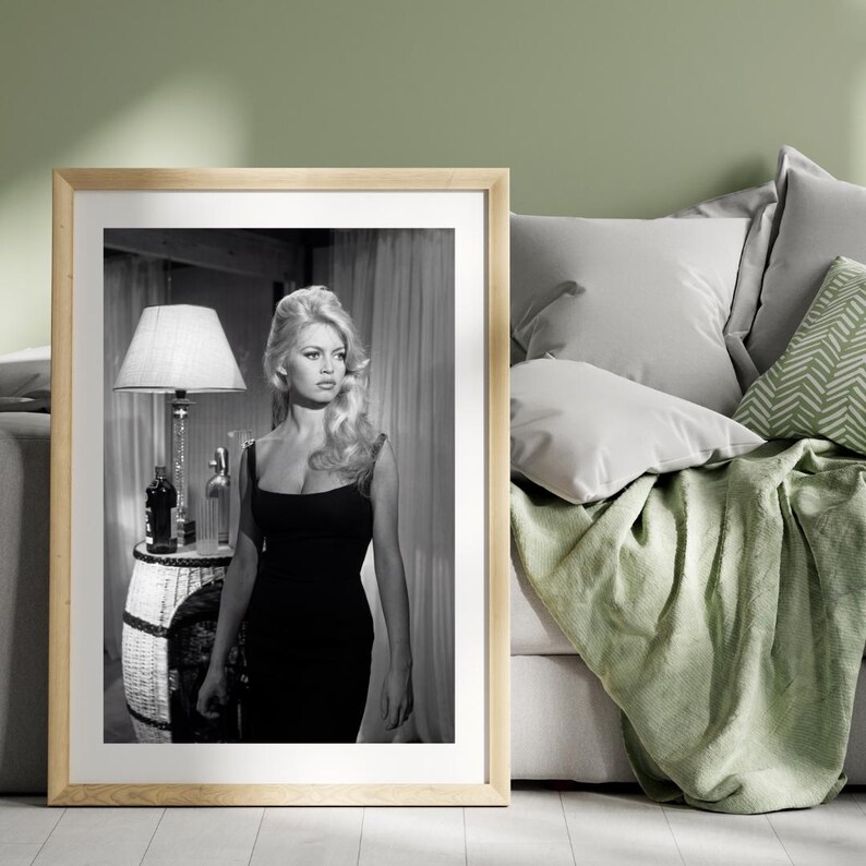 May include: A white ceramic mug with a black handle and the text "But First, Coffee" in a bold, black font. The mug is set against a blurred background, suggesting a cozy setting.