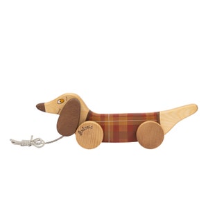 Puede incluir: Un juguete de madera en forma de dachshund con un patr&oacute;n de cuadros rojos y marrones en su cuerpo. El juguete tiene una cuerda para tirar y ruedas, y el nombre "Antonia" est&aacute; escrito en una de las ruedas.
