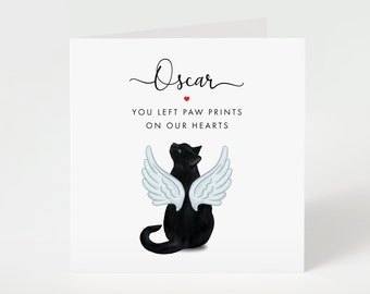 May include: A white greeting card with a black cat wearing white angel wings. The card reads "Oscar" above the text "YOU LEFT PAW PRINTS ON OUR HEARTS". A small red heart is between the name and the text.