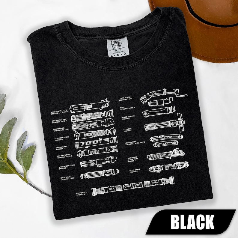 May include: Black t-shirt with a white diagram of various lightsabers from a popular science fiction franchise. The shirt includes the text "BLACK" in a white font on a black banner.