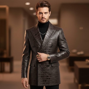 Op de afbeelding: Een bruine, dubbelknoopsluiting leren blazer met een krokodillenleertextuur. De blazer heeft een gekerfde revers, twee rijen knopen en twee voorzakken. De persoon draagt een zwarte coltrui en een gouden horloge.