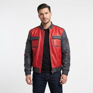 Puede incluir: Chaqueta bomber de cuero rojo y gris con cuello, puños y dobladillo de canalé. La chaqueta presenta dos bolsillos cuadrados en el pecho y mangas grises con detalles de botones rojos. Una prenda de abrigo elegante.