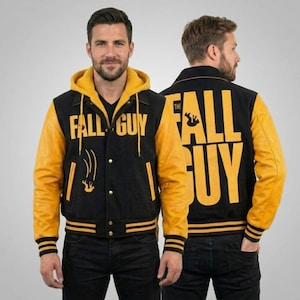 May include: Black and yellow varsity jacket featuring the text "FALL GUY". The jacket has yellow leather sleeves and a yellow hood lining. The design includes a falling figure graphic. The jacket is worn by a person.