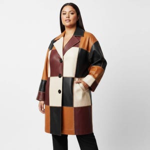 Op de afbeelding: Een patchwork leren jas in verschillende kleuren, waaronder zwart, bruin, bruin en crème. De jas heeft een klassieke reverskraag, twee voorzakken en een knoopsluiting. De jas is knielang.