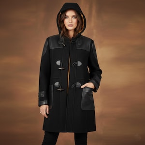 May include: A black duffel coat with a hood and leather accents. The coat features toggle closures, leather patches on the shoulders and pockets, and a yellow lining in the hood. The coat has a classic, timeless design.