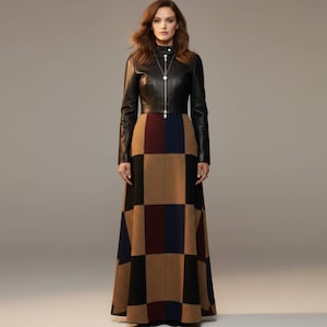 May include: A woman wearing a black leather jacket with a silver zipper and a long, checkered skirt. The skirt features a pattern of brown, black, navy, and burgundy squares. The jacket is fitted, and the skirt is floor-length.