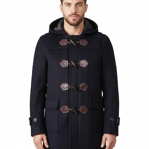 May include: A navy blue duffel coat with a hood and toggle closures. The coat features two front pockets and brown leather-like toggles. The coat is a classic outerwear piece.