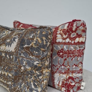 May include: Two patterned fabric pouches with zip closures. One pouch features a grey, brown, and white design, while the other has a red, grey, and white pattern. Both pouches have a small white tag attached.