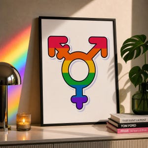 Może przedstawiać: Oprawiony wydruk artystyczny przedstawiający duży, wyśrodkowany symbol transpłciowości, wykonany w poziomym gradiencie tęczy składającym się z kolorów czerwonego, pomarańczowego, żółtego, zielonego, niebieskiego i fioletowego na białym tle w cienkiej czarnej ramie.