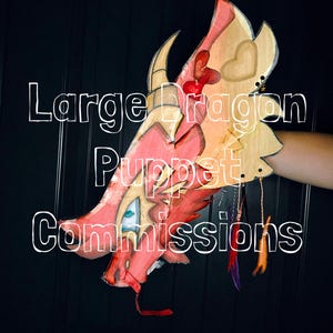 May include: A red and tan dragon puppet featuring a prominent horn, a blue eye, and dangling feather charms. The text Large Dragon Puppet Commissions is overlaid on the image. The puppet has a layered design with heart-shaped details.