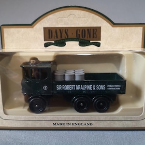 Peut inclure: Un camion jouet vert foncé avec le texte "SIR ROBERT MCALPINE & SONS" et "PUBLIC WORKS CONTRACTORS" sur le côté. Le camion est dans une boîte en carton avec les mots "DAYS GONE" et "MADE IN ENGLAND".