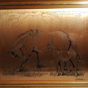以下が含まれることがあります： 木製のフレームに入った銅色の芸術作品。 雌馬と子馬が野原にいる様子が描かれており、雌馬の頭は下がり、子馬は彼女の隣に立っています。 背景には雲の多い空があります。 「Joel Kirk」のサイン入り。