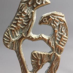 May include: A detailed brass sculpture featuring two birds perched on a branch. The birds have textured feathers and are facing each other. The sculpture has a vintage look with a slightly tarnished finish.