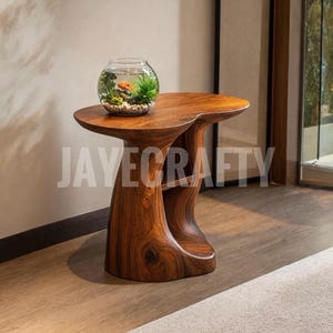 Könnte beinhalten: Ein handgefertigter Beistelltisch aus Holz mit einem einzigartigen, fließenden Design. Der Tisch hat eine warme, braune Farbe und eine runde Oberseite. Ein Glasfischglas mit einem Goldfisch und Wasserpflanzen steht darauf. Der Text "JAVECRAFTY" ist sichtbar.