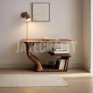 Puede incluir: Una consola de madera hecha a mano con un diseño único y orgánico. La mesa presenta una tapa de borde vivo, un estante incorporado y una base escultural. Libros y una pequeña planta se exhiben en el estante. El texto "JAYECRAFTY" es visible.