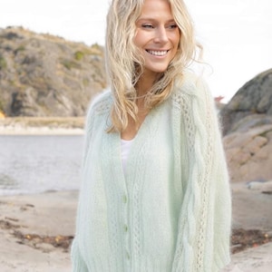 May include: A pale mint green V-neck cardigan featuring a fuzzy, soft-textured knit with vertical cable knit detailing along the sleeves and front panels, finished with a ribbed hem and cuffs and three matching buttons down the center front.